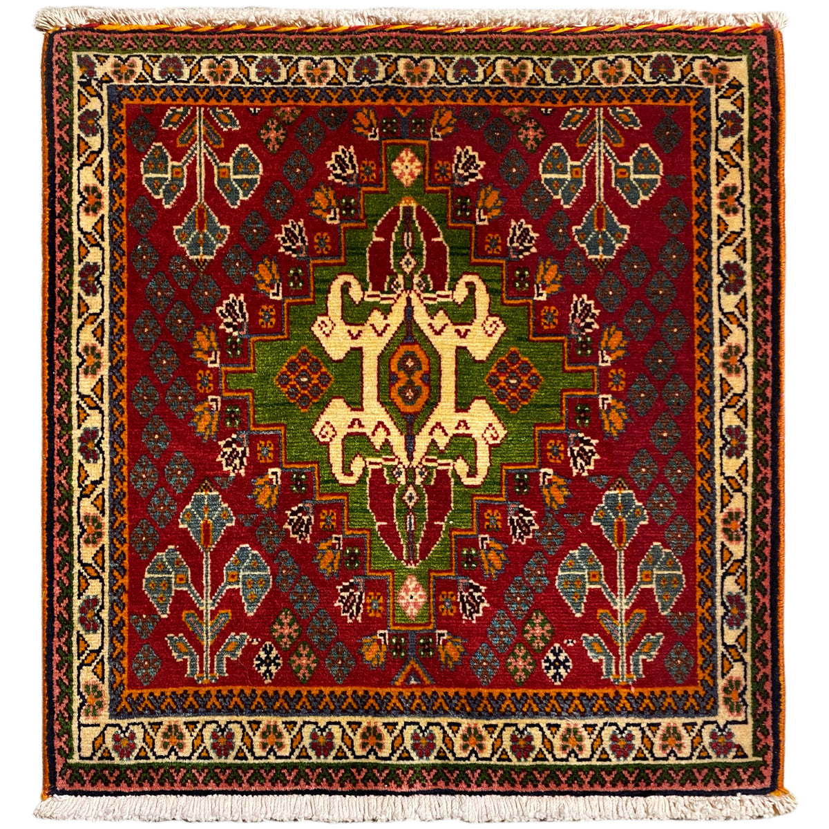 Alfombra oriental con un estampado en rojo intenso, verde y beige, cuadrada y con flecos
