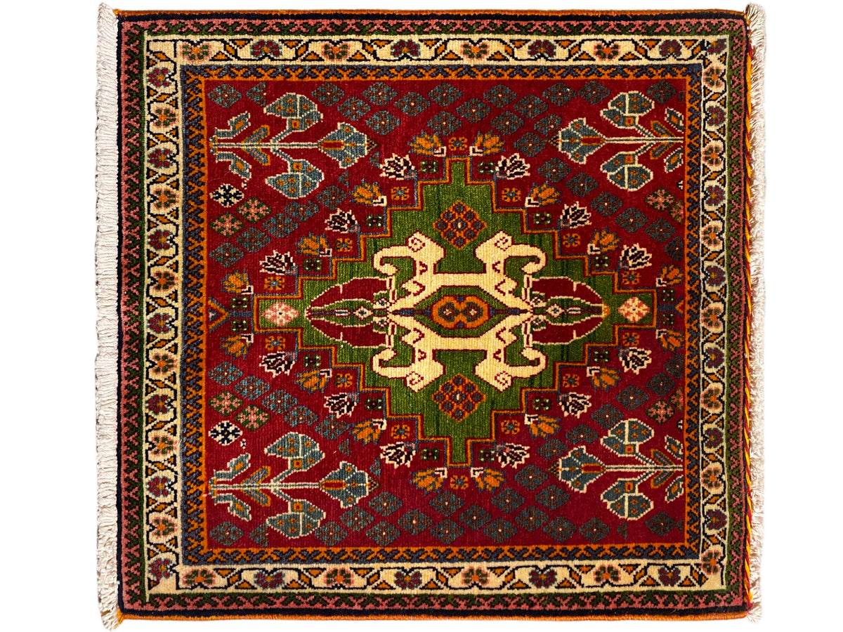 Alfombra oriental con fondo rojo, patrón de medallón en tonos verde y beige, cenefa perimetral y flecos