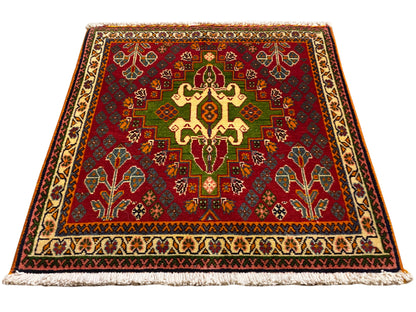 Alfombra oriental con motivo central rojo, detalles verdes y borde beige, con flecos