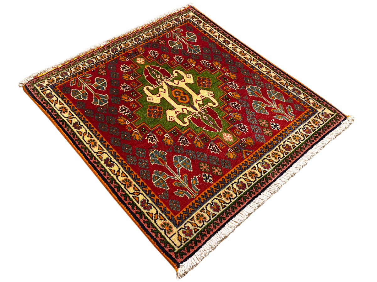 Alfombra oriental roja con ornamentos de cruces y motivos vegetales, detalles verdes y cenefa decorativa