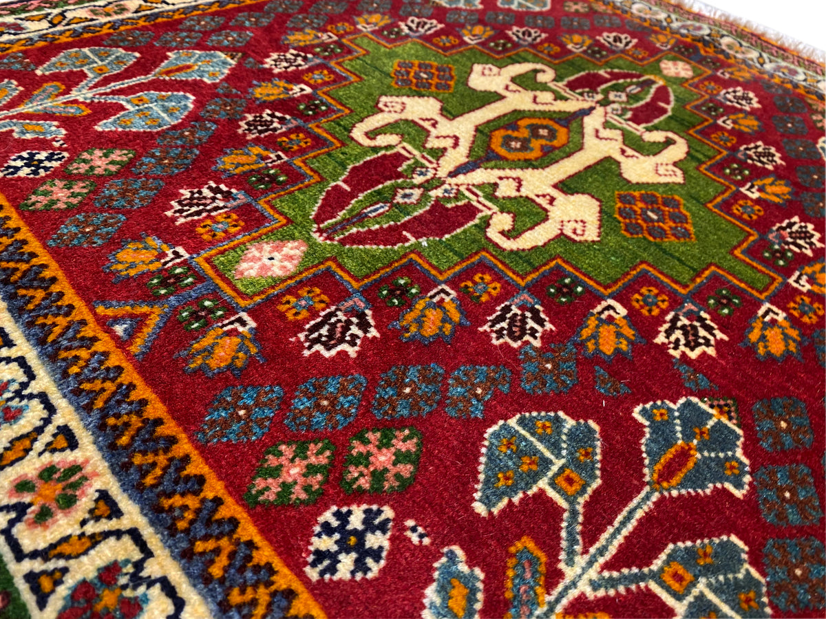 Vista de cerca de la alfombra oriental: campo rojo con motivos florales, detalles verdes