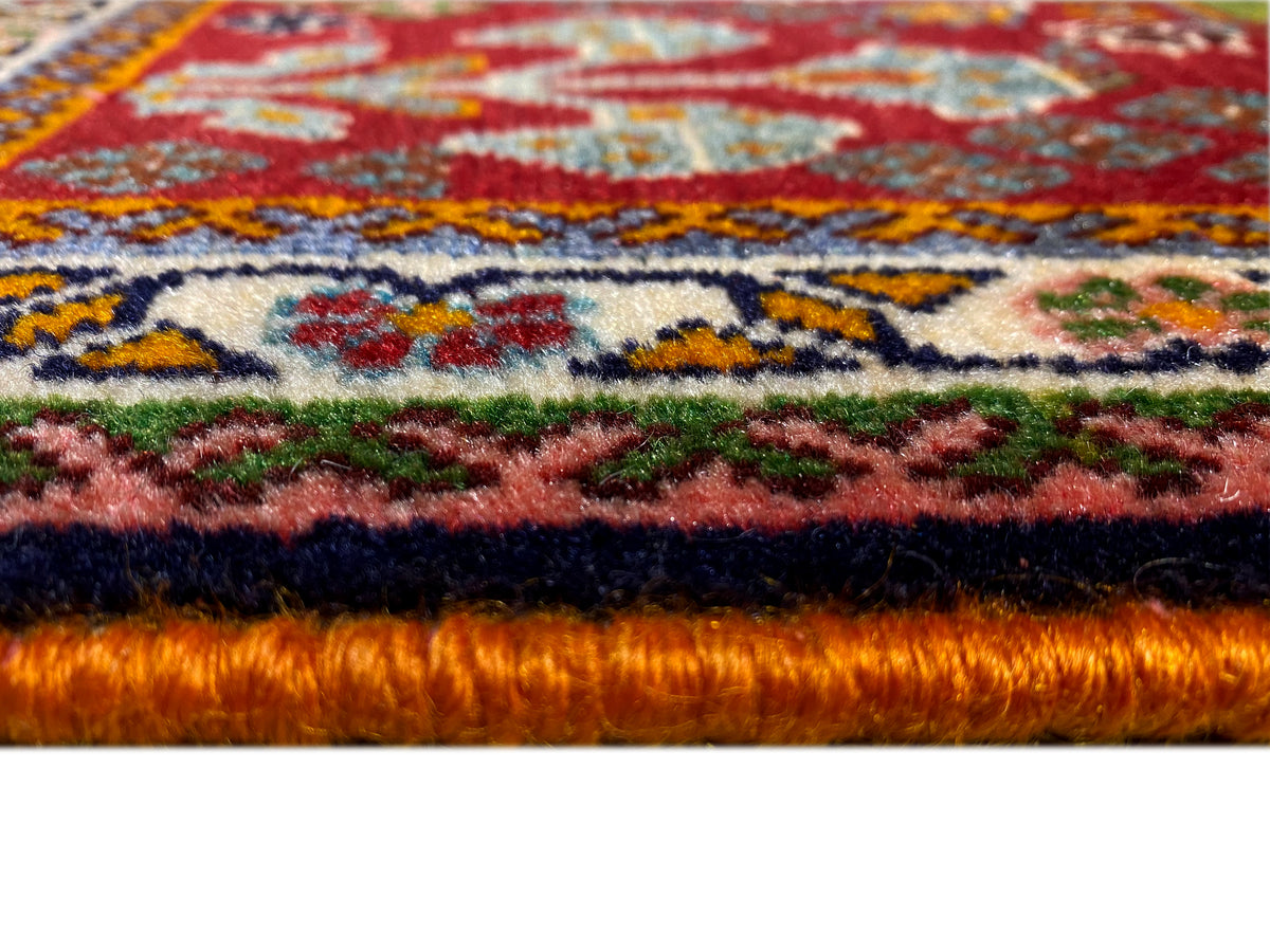Borde de la alfombra en detalle: pelo denso con fondo rojo y ornamentos de colores