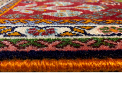 Borde de la alfombra en detalle: pelo denso con fondo rojo y ornamentos de colores