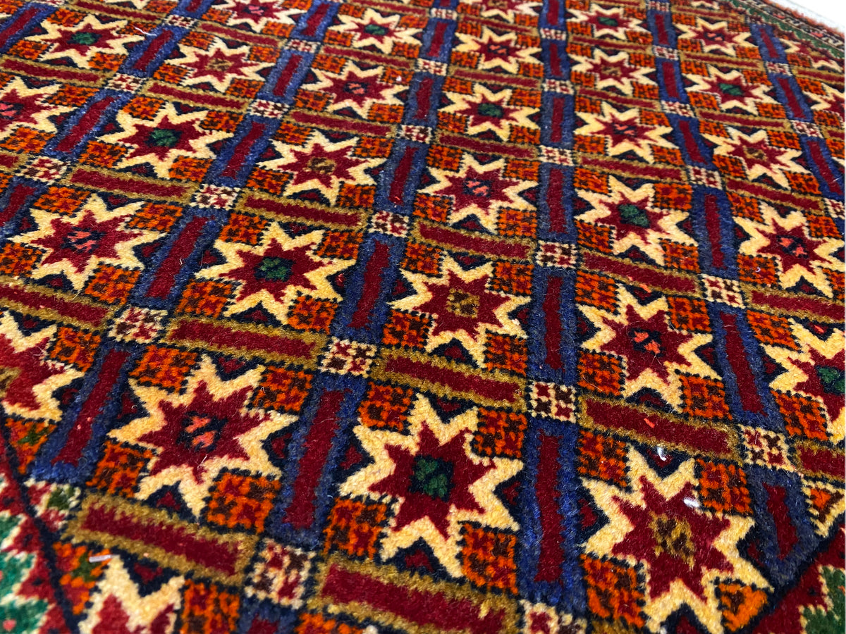 Alfombra Poshti de 62x52 cm, primer plano de la estructura tejida con motivos de estrellas y rombos.