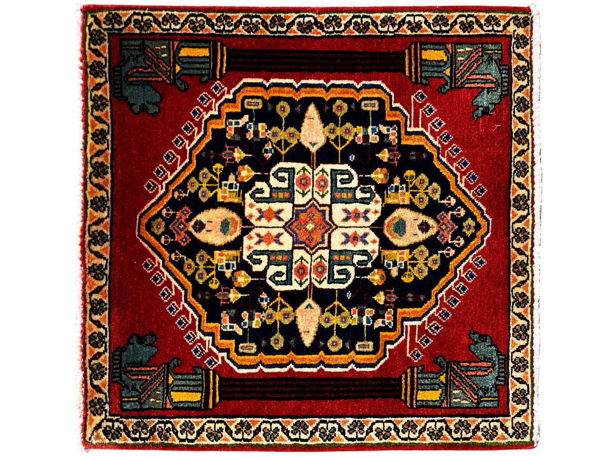 Alfombra Poshti con fondo rojo, medallón oscuro y coloridos estampados en el centro