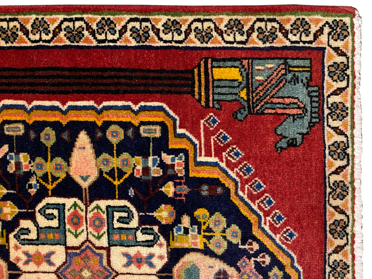 Vista de cerca de una alfombra Poshti: cenefa roja con motivos decorativos en las esquinas y bandas ornamentales