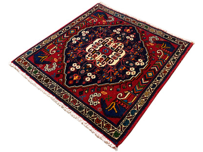 Alfombra cuadrada con borde decorativo, patrón rojo y azul y centro de color crema