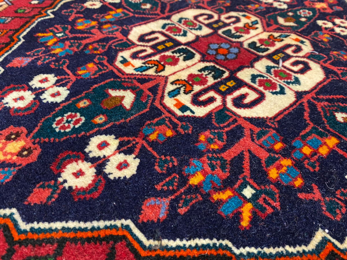Vista de cerca del pelo de la alfombra con ornamentación de colores en azul, rojo, crema y verde