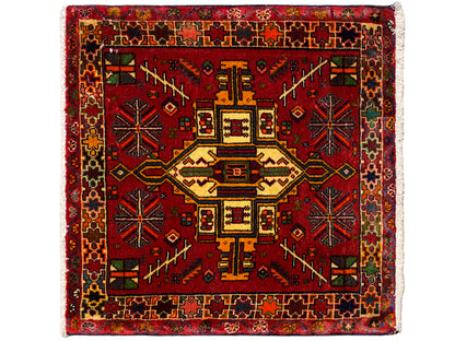 Alfombra Poshti rectangular con fondo rojo y motivo central geométrico, multicolor