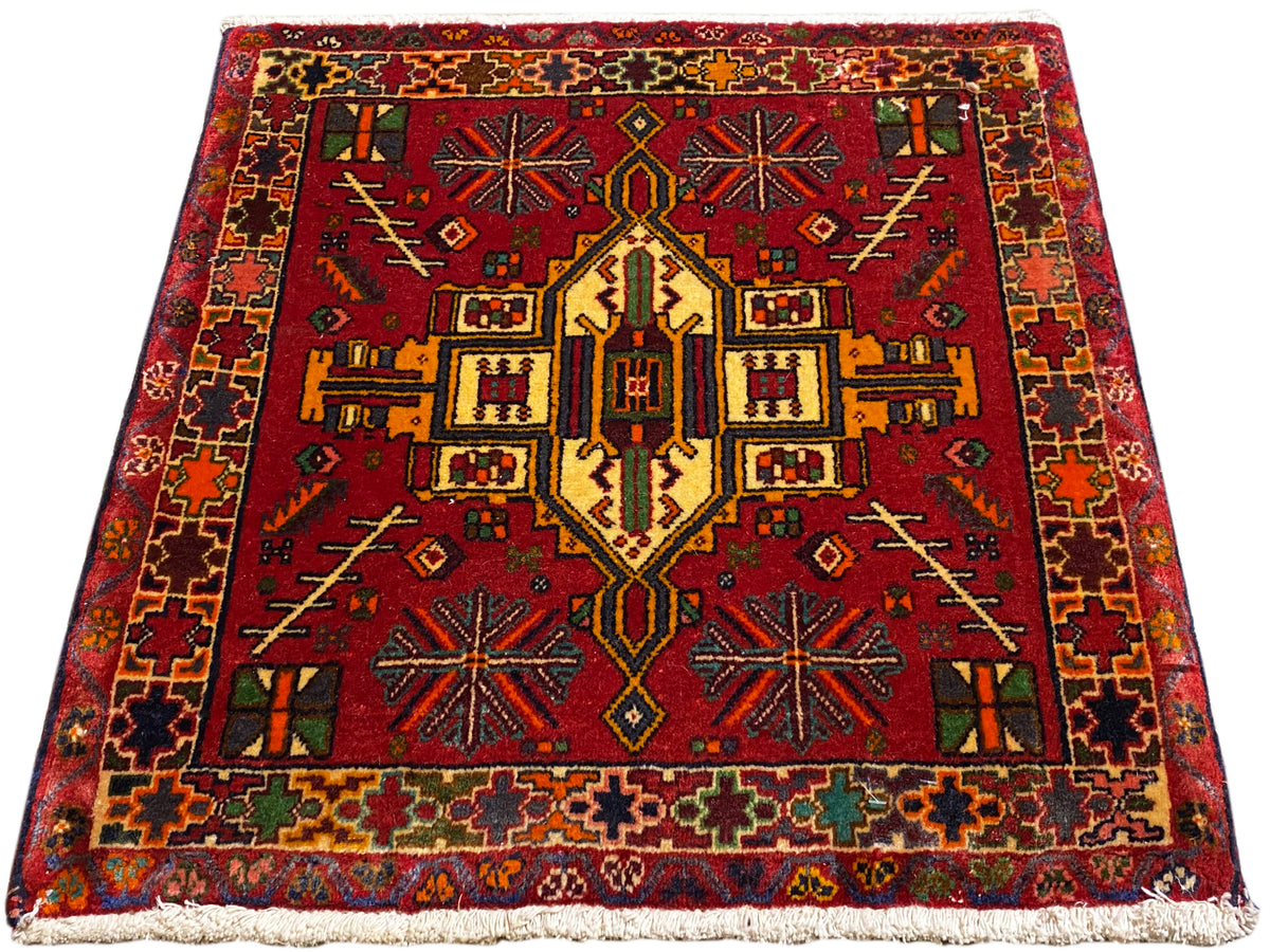 Alfombra Poshti roja con diseño central simétrico y borde multicolor