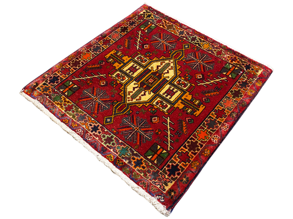 Alfombra Poshti con fondo rojo y diseño geométrico, borde multicolor, rectangular