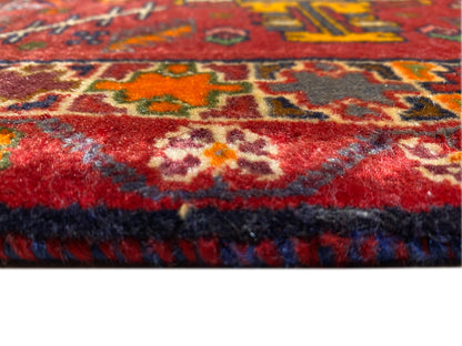 Primer plano del borde de la alfombra con pelo rojo y ribete multicolor