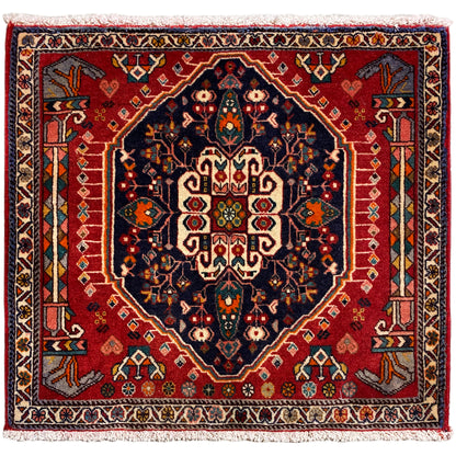 Alfombra cuadrada con fondo rojo y motivo central azul oscuro, con flecos