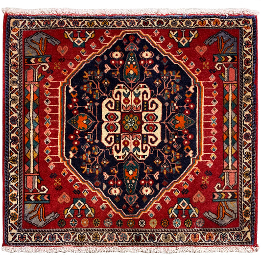 Alfombra cuadrada con fondo rojo y motivo central azul oscuro, con flecos