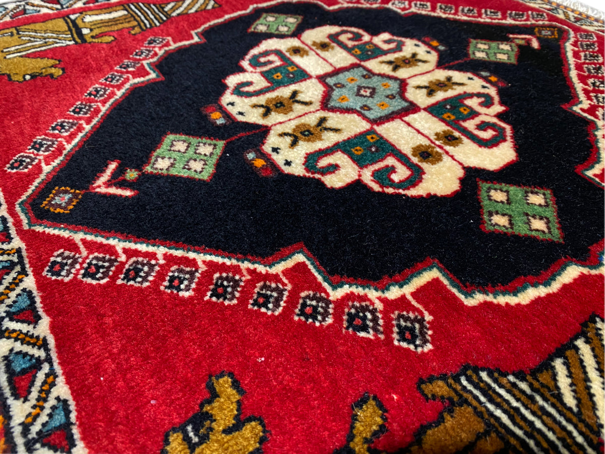 Alfombra Poshti de 63x55 cm: primer plano del medallón central con un diseño rojo y negro