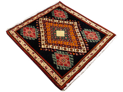 Alfombra Poshti extendida en vista de diamante: fondo negro, motivos naranjas y campos rojos/verdes