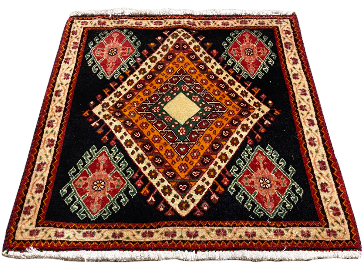 Alfombra Poshti cuadrada con fondo negro, composición central de rombos y un marco decorativo perimetral