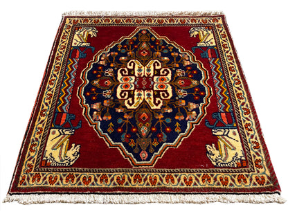 Alfombra rectangular con fondo rojo, azul oscuro y bordes con motivos beige