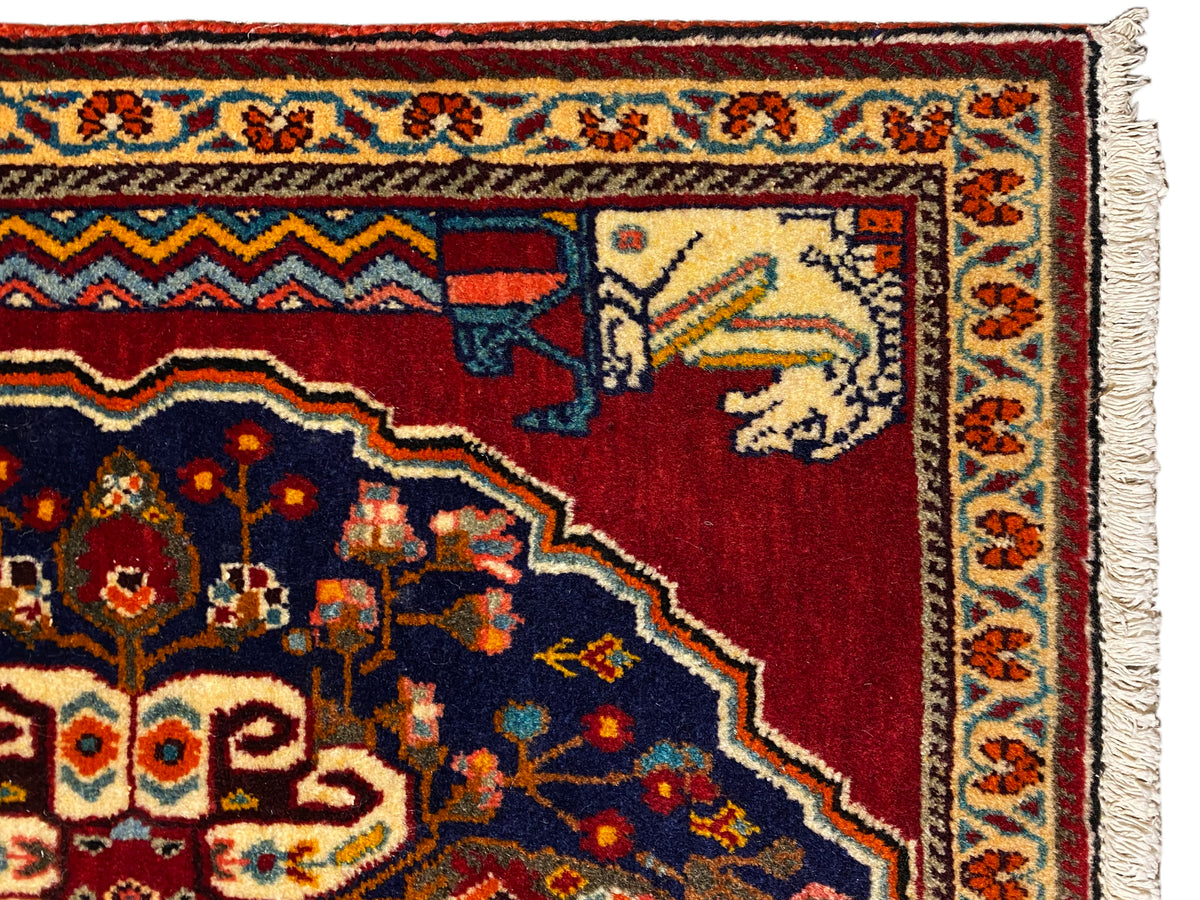 Vista detallada: patrón de alfombra rojo y azul oscuro con elementos de animales y figuras en beige