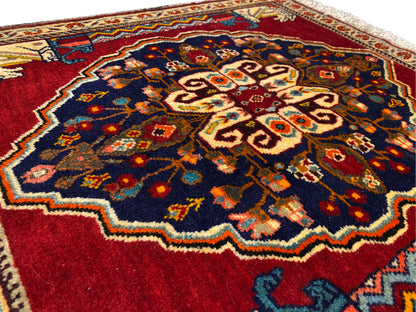 Primer plano del centro de la alfombra: azul oscuro, rojo, beige y superficies ornamentales multicolores
