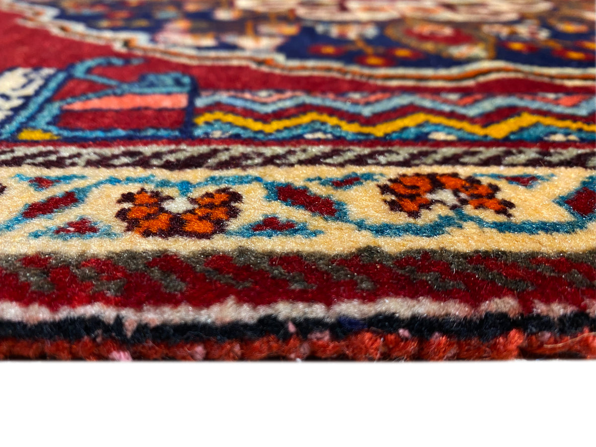Primer plano de un detalle de la alfombra: cenefa de colores, ornamentos multicolores y una densa estructura de pelo.