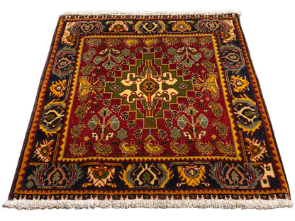 Alfombra con campo interior rojo, ornamentos geométricos y un borde corto de flecos