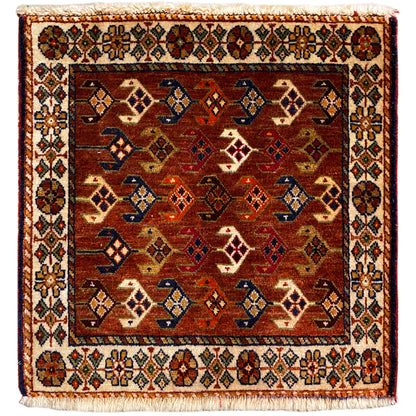 Alfombra Poshti de 60x55 cm con diseño geométrico en rojo, marrón, azul y crema