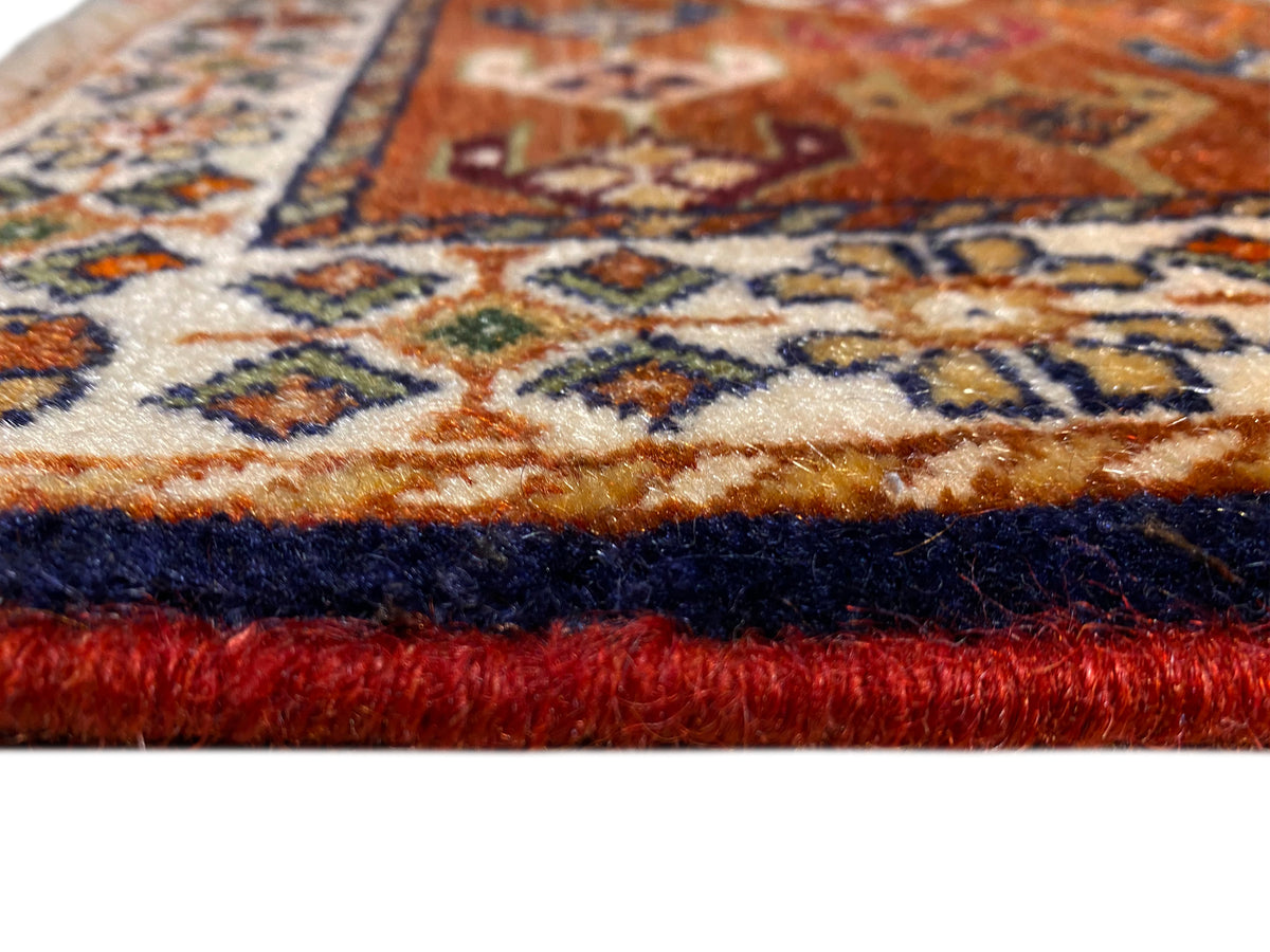 Alfombra Poshti de 60x55 cm en primer plano: flecos y patrón de tejido multicolor en el borde