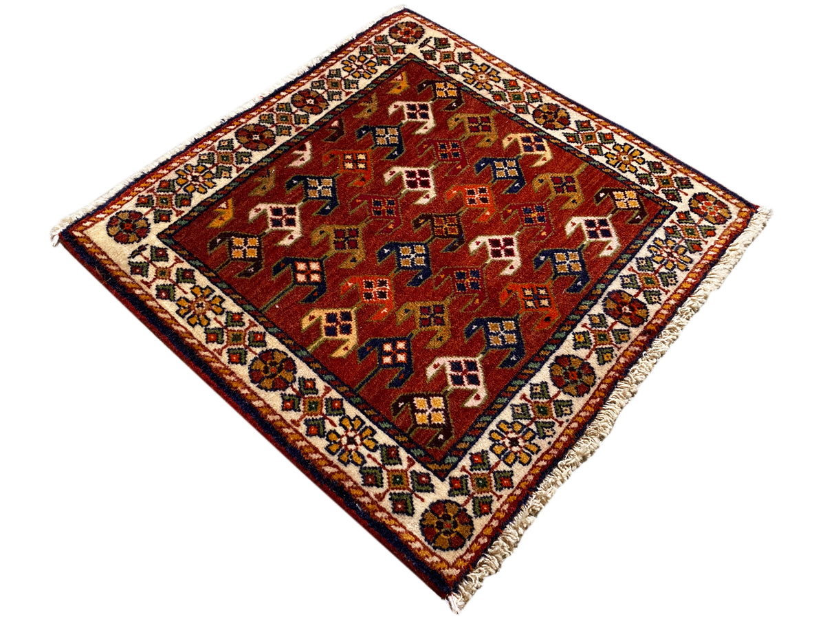 Alfombra de 61x61 cm con fondo rojo y coloridos motivos geométricos, cenefa perimetral