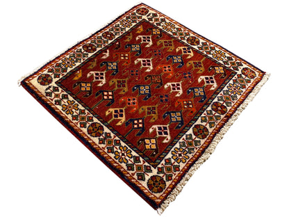 Alfombra de 61x61 cm con fondo rojo y coloridos motivos geométricos, cenefa perimetral
