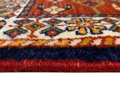 Borde de alfombra con pelo rojo, remate oscuro y franja de diseño ornamental