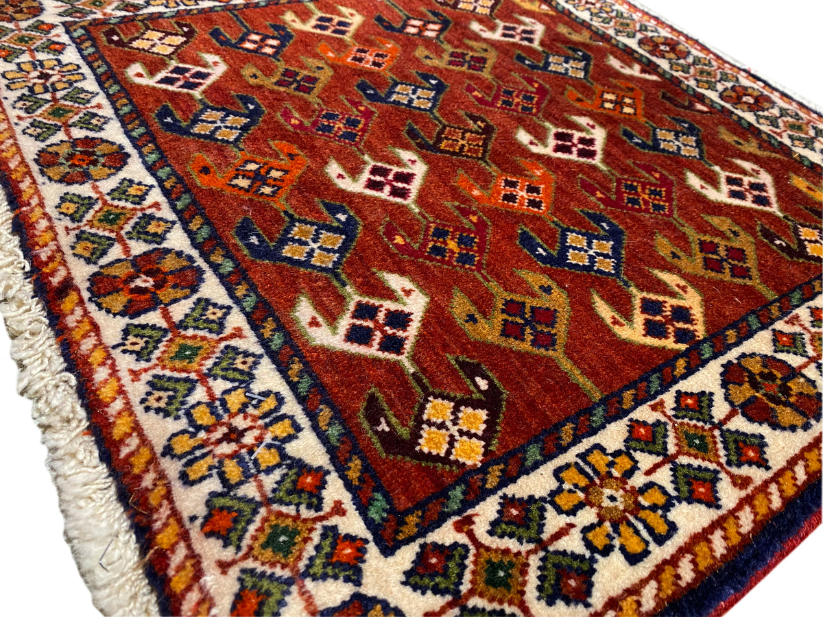 Alfombra con campo de diseño rojo, marco azul turquesa y borde deshilachado