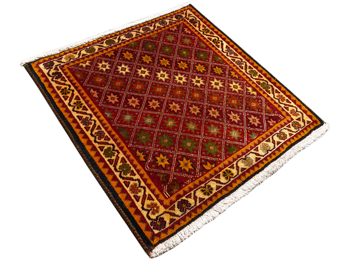 Alfombra Poshti, rectangular, vista diagonal: campo interior rojo con motivos de estrellas y cenefa.