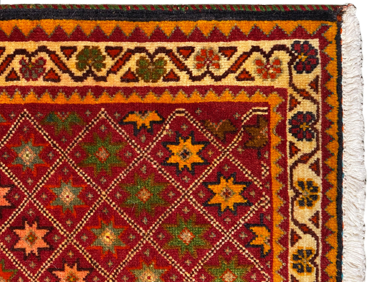Vista detallada de la alfombra Poshti: cenefa ornamental colorida y diseño denso en el campo interior.