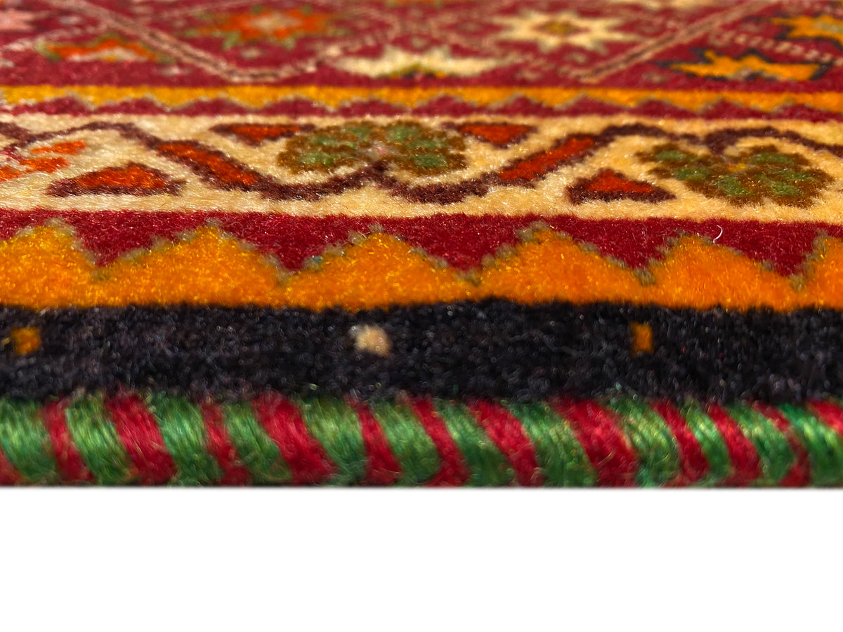 Detalle del borde de la alfombra Poshti: flecos de colores y pelo corto sobre un fondo blanco.