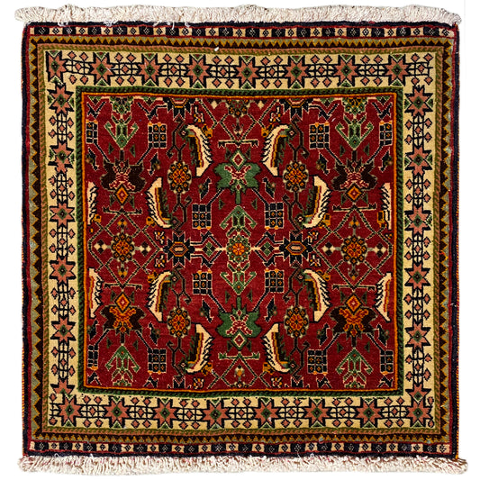 Alfombra Poshti de 63x61 cm con estampado rojo y verde y flecos en el borde.