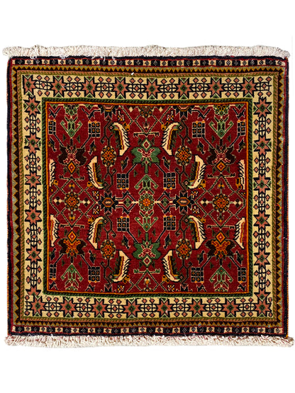 Alfombra poshti rectangular de 63x61 cm con estampado rojo, borde multicolor y flecos.