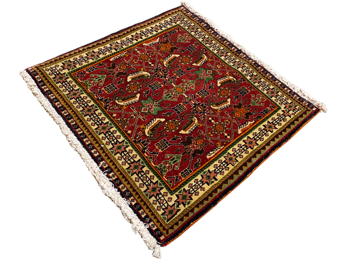Alfombra Poshti de 63x61 cm, vista diagonal de cerca: alfombra roja con ornamentos y flecos.
