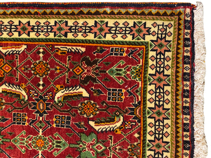 Alfombra Poshti de 63x61 cm, vista detallada: campo ornamental rojo con motivos verdes y amarillos.