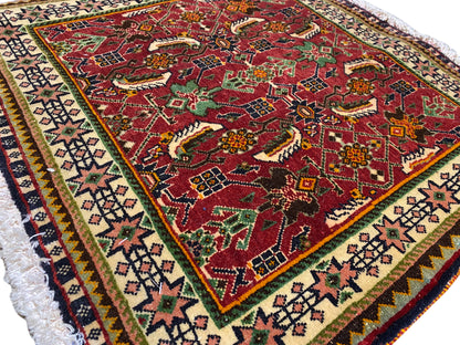 Alfombra Poshti de 63x61 cm, vista detallada: patrón rojo con motivos de animales y ornamentos, y cenefa.