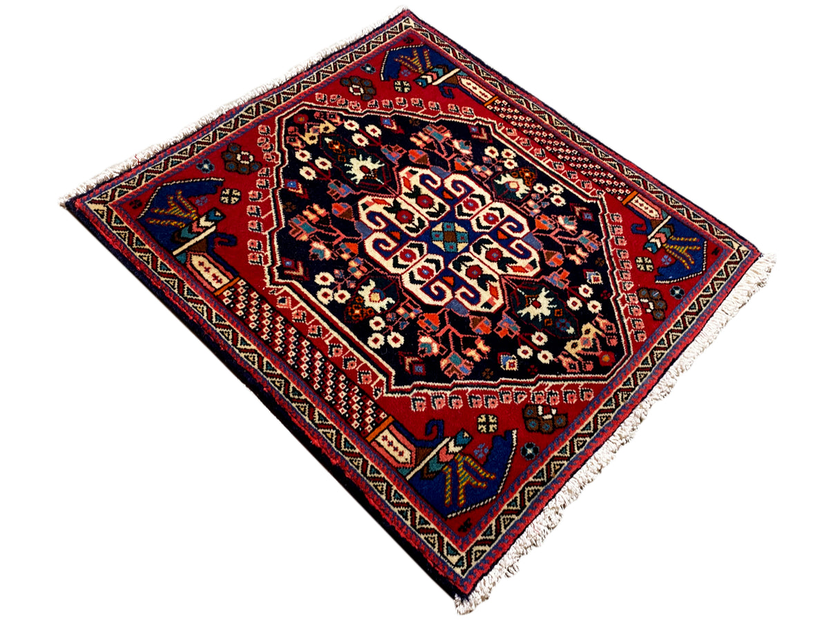 Alfombra Poshti de 66x63 cm, campo azul oscuro, marco rojo y motivos florales