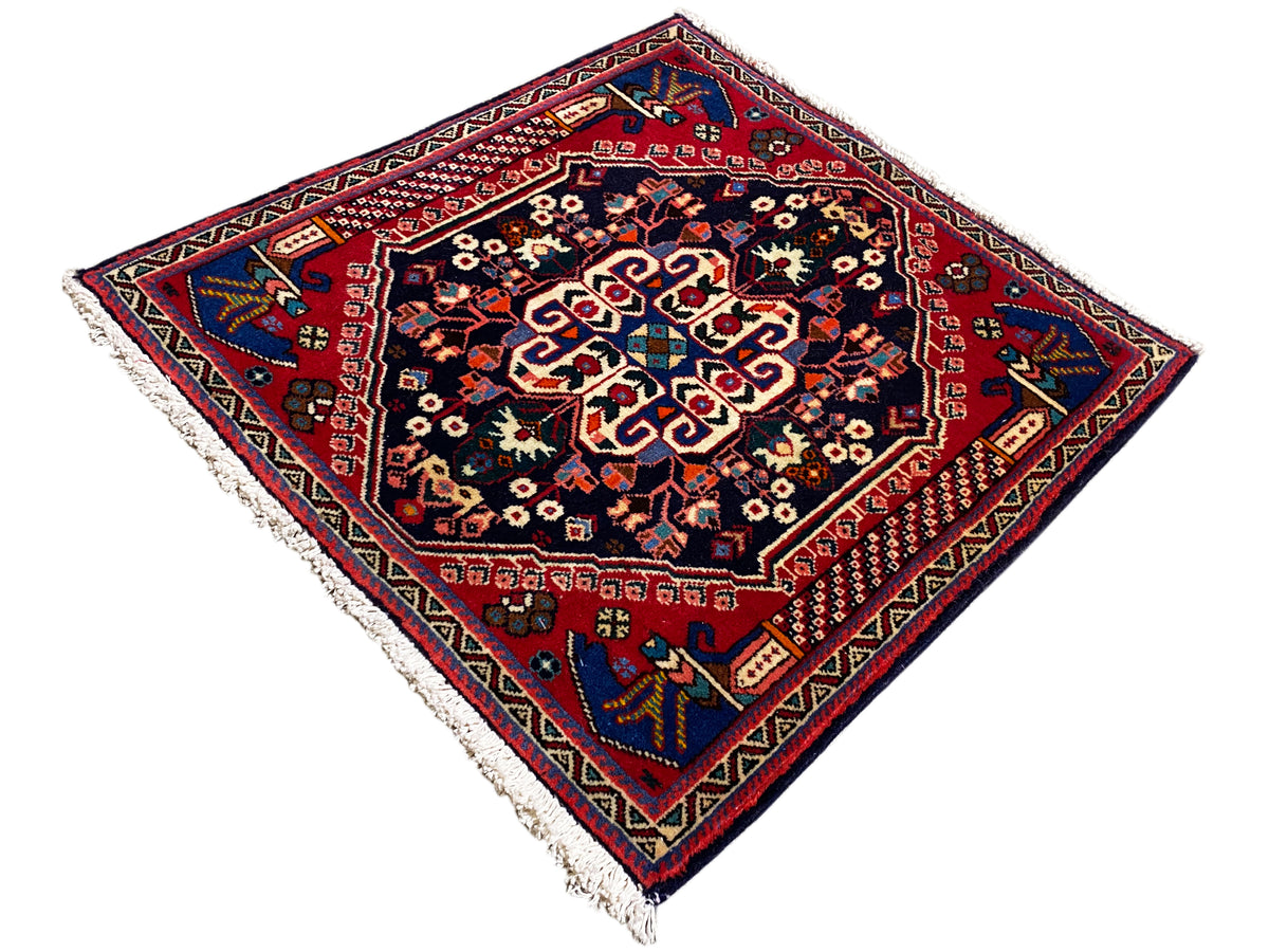 Alfombra Poshti de 66x63 cm, medallones multicolores, base oscura y borde rojo