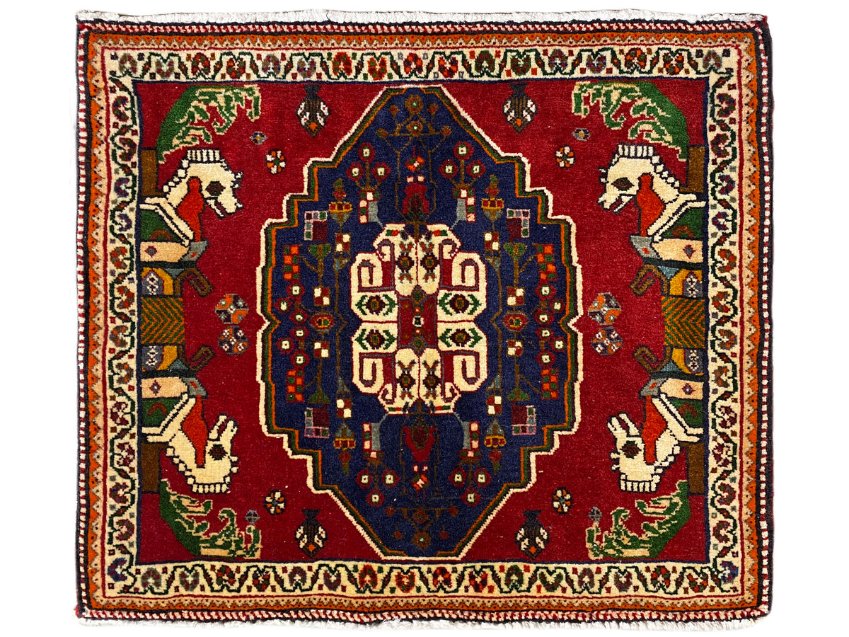 Alfombra Poshti con fondo rojo, medallón central azul y cenefa decorativa