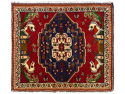 Alfombra Poshti con fondo rojo, medallón central azul y cenefa decorativa
