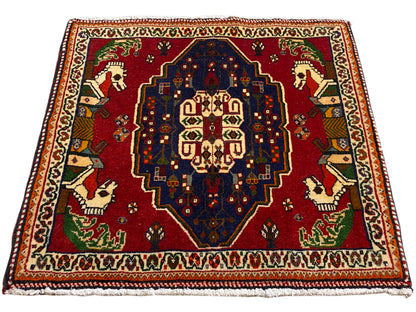 Alfombra Poshti cuadrada, base roja, medallón central azul y cenefa multicolor