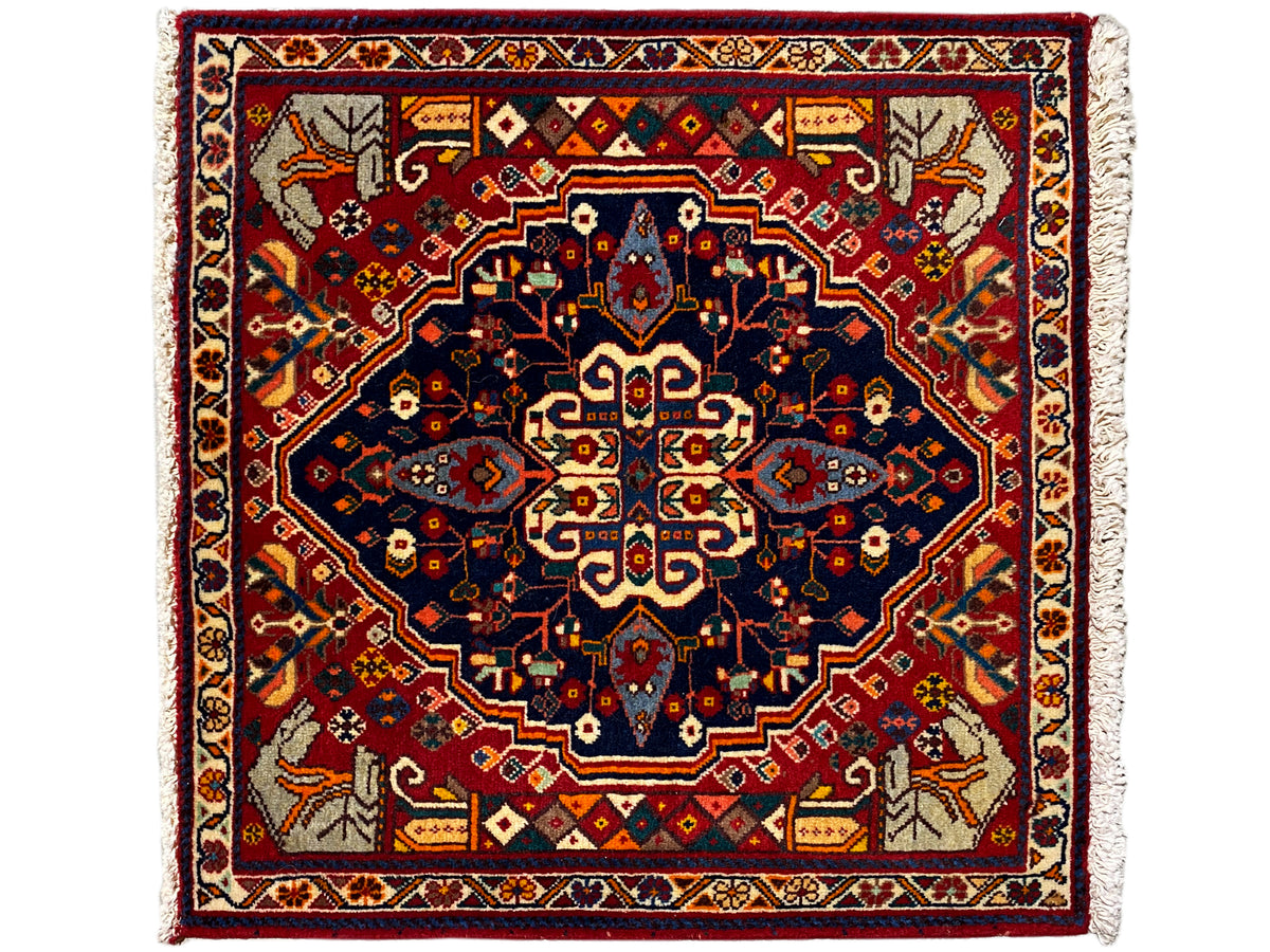 Alfombra cuadrada con fondo rojo, estrella de diseño azul y cenefas decorativas