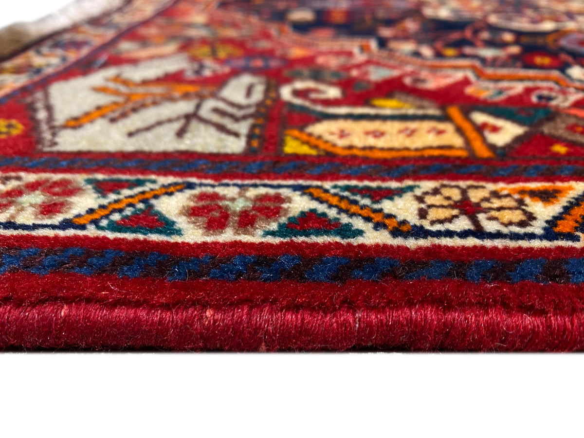 Detalle de alfombra en el dobladillo: cenefa roja y azul, motivos multicolores y flecos cortos