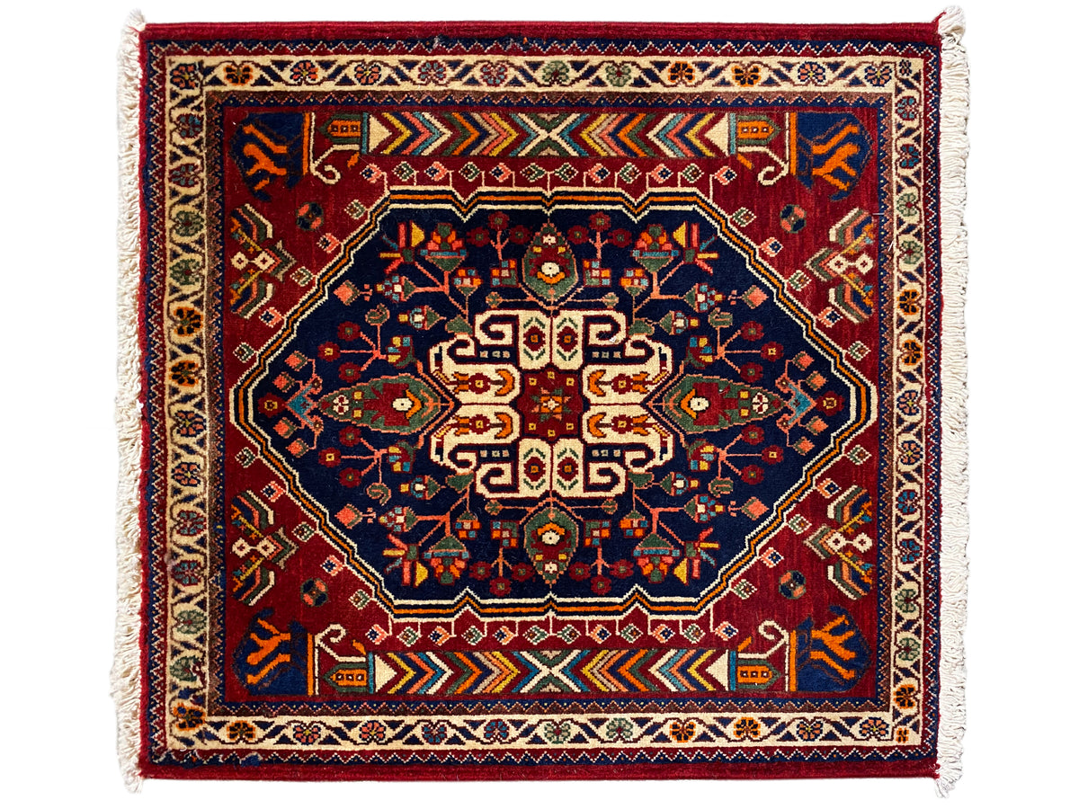 Alfombra de 63x60 cm en azul oscuro con estampado rojo, franjas enmarcadas y flecos