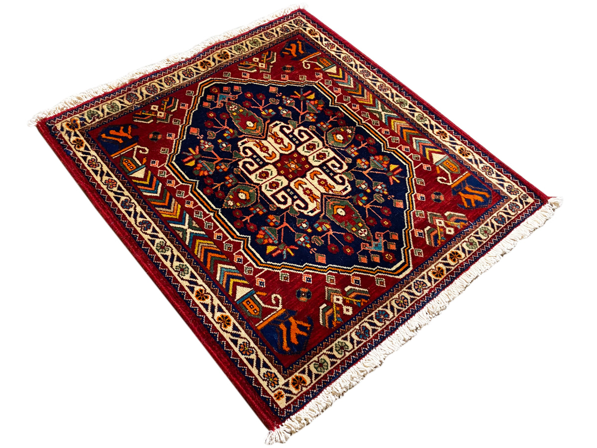 Alfombra de 63x60 cm con patrón ornamental geométrico, parte central azul y flecos