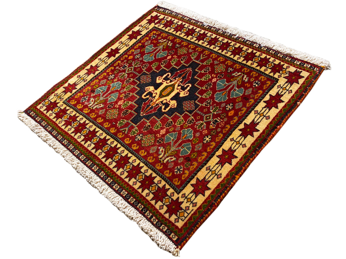 Alfombra de 60x58 cm, vista diagonal: campo rojo con centro negro, flecos